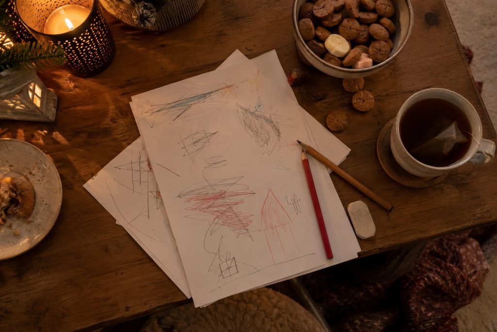 Keukentafel van bovenaf met kladpapier, een potlood, een gum, thee en pepernoten